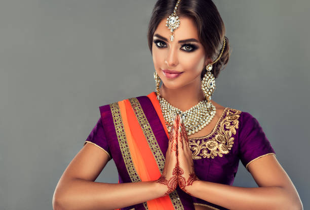 Perfect Indian woman is demonstrating welcome gesture. Portrait of beautiful indian girl dressed in a traditional national suit (sari), mehndi henna tattoo is painted on her hands and traditional kundan style jewelry set on her.